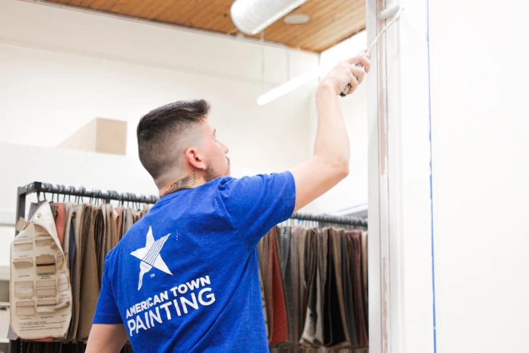 A man in a blue shirt painting a wall, representing the theme of American Town Painting.