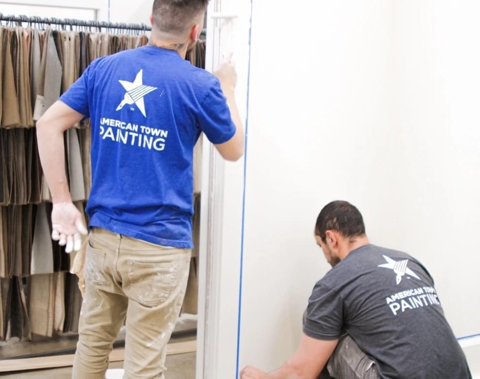 Two men painting a wall in a room, showcasing the work of American Town Painting.